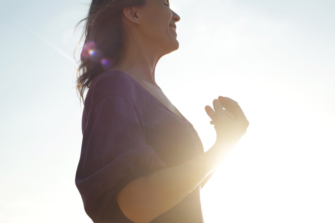 Judith in silhouet tegen de zon, handen rustend op haar hart